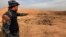 A member of Iraqi security forces gestures towards a mass grave for corpses in the town of Hammam al-Alil which was seized from Islamic State last week, Nov. 9, 2016. 