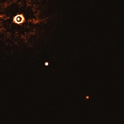 This image from the European Southern Observatory, July 2020, shows the star TYC 8998-760-1, upper left, and two exoplanets. The image was captured by blocking the light from the star, allowing for the fainter planets to be detected.