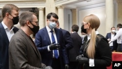 Ukraine's parliament speaker Dmytro Razumkov, center, and former Prime Minister Yulia Tymoshenko, right, wearing face masks to protect against coronavirus talk at an extraordinary parliamentary session in Kyiv, Ukraine, March 30, 2020.