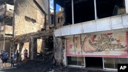 Reporters work by a charred building in Pointe-a-Pitre, Guadeloupe, Nov.21, 2021. France is sending special police forces to the Caribbean island, a French overseas territory, as protests over COVID-19 restrictions there erupted into rioting. 