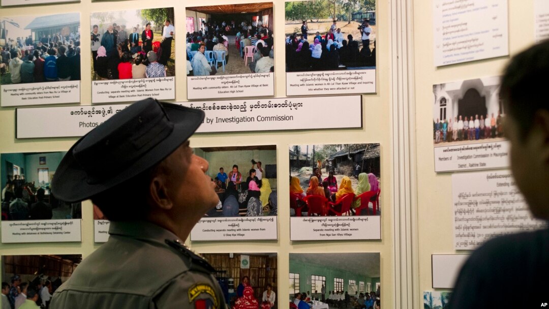A Myanmar police officer looks at photos displayed during a press conference of Maungdaw Investigation Commission at a government guest house Sunday, Aug.6, 2017, in Yangon, Myanmar. The Myanmar government's inquiry into violence in northern Rakhine state last year that forced tens of thousands of Muslim Rohingya to flee to Bangladesh and led to U.N. accusations of crimes against humanity by the army has concluded that no such crimes happened.