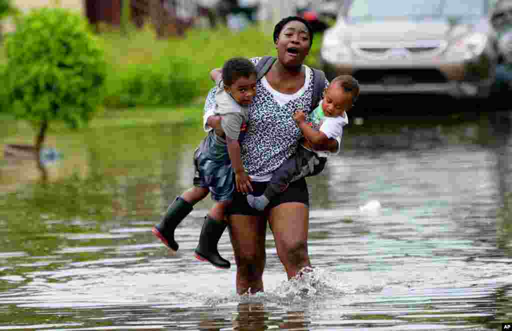 Terrian Jones reacts when she feels something moving in the water at her feet as she carries Drew and Chance Furlough to their mother on Belfast Street in New Orleans, Louisiana, during flooding from a storm in the Gulf Mexico, July 10, 2019.