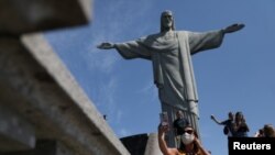 Turistas toman fotos bajo la estatua del Cristo Redentor durante la reapertura del monumento tras el cierre por causa de la pandemia del COVID-19- Río de Janeiro, 15 de agosto 2020. 
