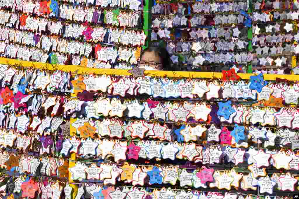 A woman hangs a paper note with her New Year wishes on a wire at a Buddhist temple in Seoul, South Korea.