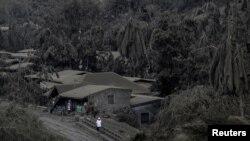 A man walks on a road covered with ashes from the Taal Volcano in Talisay, Batangas, Philippines.