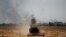 FILE - Smoke billows from the positions of the Islamic State militants as a harvester gathers the wheat crop from a field in western Mosul, Iraq, June 19, 2017.
