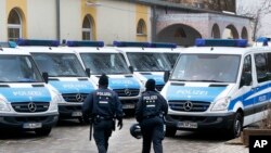 FILE - German police officers walk in front of a mosque during a terror raid in Frankfurt, Germany, Feb. 1, 2017. 