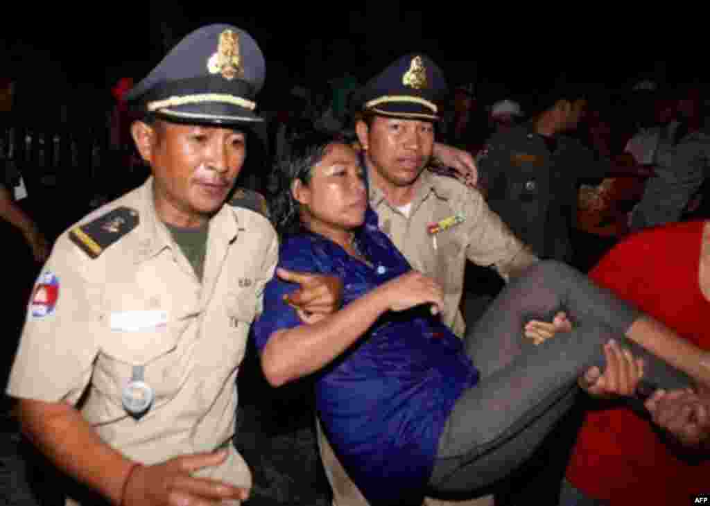 An injured visitor is carried by Cambodian police and another visitor after a stampede onto a bridge at an accident site during the last day of celebrations of the water festival in Phnom Penh, Cambodia, Monday, Nov. 22, 2010. Thousands of people celebrat