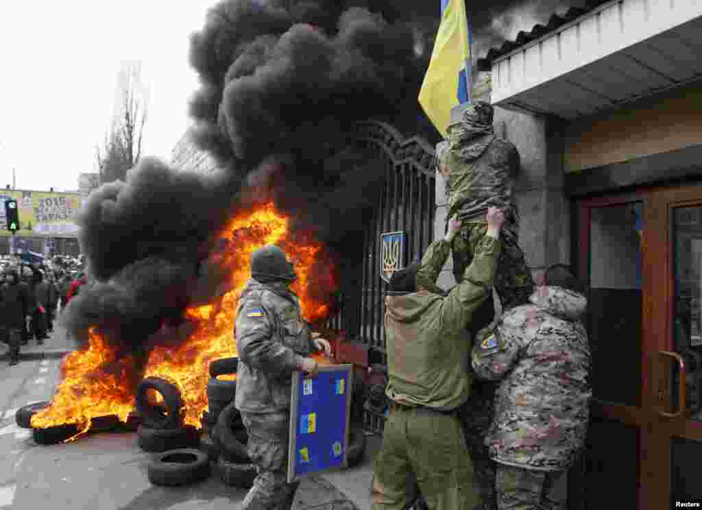 Servicemen from the battalion &quot;Aydar&quot; remove a Ukrainian flag from the Ukraine&#39;s Defense Ministry during a protest against the disbanding of the battalion, in Kyiv, Feb. 2, 2015.