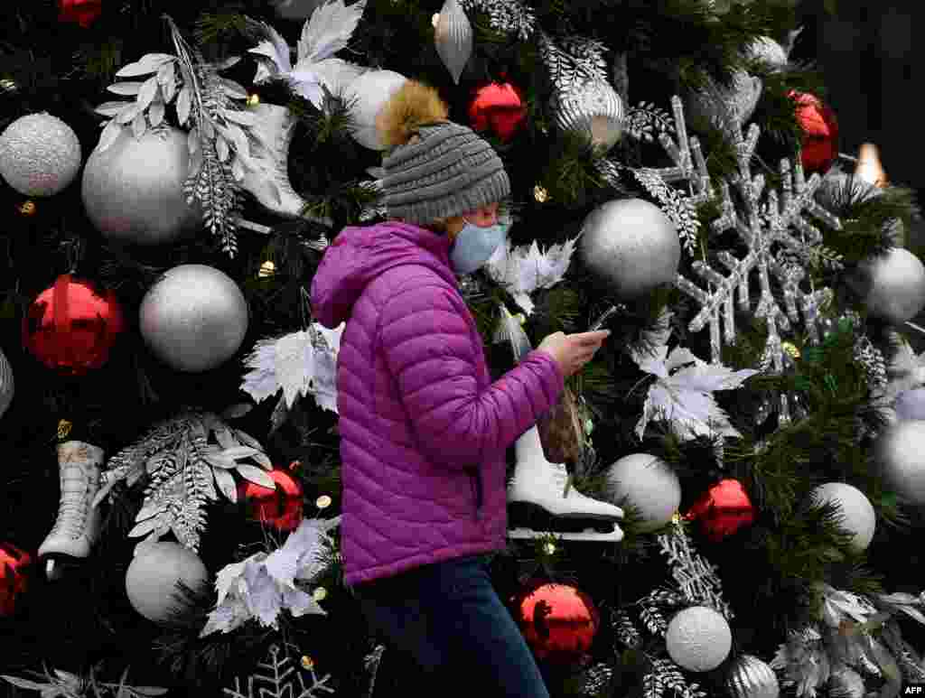 Una mujer con una mascarilla pasa junto a un &#225;rbol de Navidad decorado en medio de la pandemia de COVID-19 en Arlington, Virginia, el 18 de diciembre de 2020. [AFP]