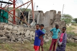 Children look at a damaged telecommunications mast after an attack by al-Shabab extremists in the settlement of Kamuthe in Garissa county, Kenya, Jan. 13, 2020.