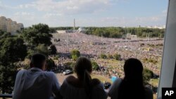 People watch as Belarusian opposition supporters rally in the center of Minsk, Belarus, Aug. 16, 2020. 