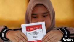 Seorang pemilih pemula memasukkan surat ke kotak suara di sebuah TPS di DKI Jakarta, 17/4. 