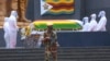 Pallbearers stand next to the coffins of three top government officials prior to their burial, at the National Heroes Acre in Harare, Wednesday, Jan. 27, 2021. 