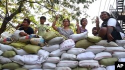 People flash the three-fingered symbol of resistance from behind a barricade of sacks blocking a road in Mandalay, Myanmar, March 5, 2021.