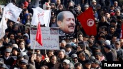 Tunisians hold a placard with an image of the late secular opposition leader Chokri Belaid during his funeral procession in the Jebel Jelloud district in Tunis, February 8, 2013. 