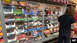 A shopper passes by refrigerated cases displaying packages of bacon in a grocery store in southeast Denver, Oct. 7, 2024. 