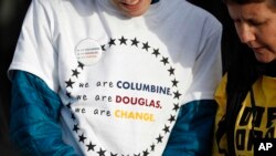 A student wears a printed message during the kickoff event for the Vote For Our Lives movement to register voters, April 19, 2018, at Clement Park in Littleton, Colo. The event was held on the eve of the 19th anniversary of the shootings at Columbine High School.