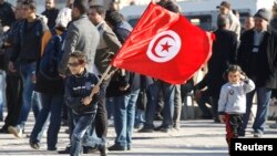 Un Tunisien marchent lors d'un rassemblement un an après la fin de la dictature à Tunis, Tunisie, le 17 décembre 2013.