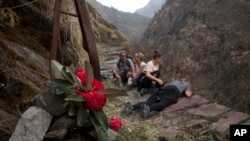 FILE - In this March 27, 2017 photo, Elizabeth Brenner, third right, and her family sit at the spot on the Milam Glacier Trail where Brenner's son, Thomas Plotkin, slipped and fell more than 300 feet down a steep gorge and into the raging Goriganga river in 2011.