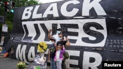 Keluarga Forbes dari Bowie, Maryland, berfoto di depan spanduk Black Lives Matter dekat Gedung Putih, Washington, 10 Juni 2020.