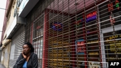 A woman talks on the phone as she stands outside of a closed nail parlour and spa salon in downtown Atlanta, Georgia, on April 23, 2020. - The US state of Georgia takes a massive gamble on April 24 when it allows businesses like gyms and hair salons…