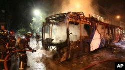 Firefighters put out the flames on a burning bus during a protest against the rising cost of subway and bus fares, in Santiago, Chile, Oct. 18, 2019. 