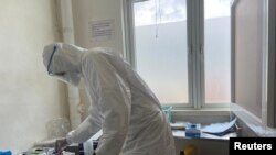 FILE - A member of medical staff wearing protective equipment, prepares to take care of patients amid the spread of the coronavirus disease (COVID-19), at an hospital in Douala, Cameroon, Apr. 27, 2020.