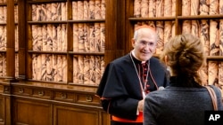 The Vatican Apostolic Librarian, Cardinal José Tolentino de Mendonça, left, speaks to a reporter, Monday, November 8, 2021, during the presentation to the media of the exhibition 'Tutti' inside the Apostolic Library. (AP Photo/Nicole Winfield)