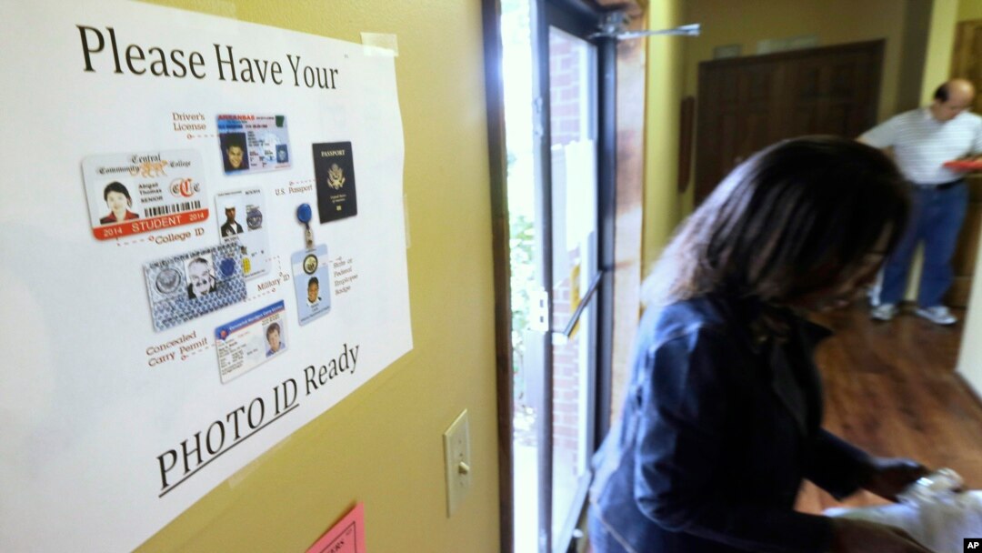 FILE - An election worker walks past a voter ID sign at a polling place in Little Rock, Arkansas, May 20, 2014.