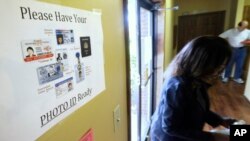 FILE - An election worker walks past a voter ID sign at a polling place in Little Rock, Arkansas, May 20, 2014.