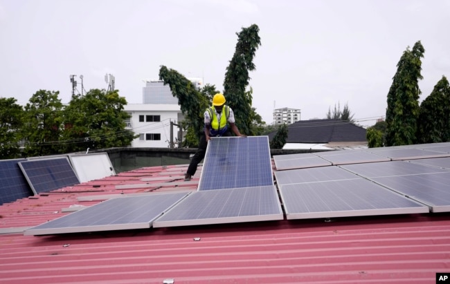 FILE - Oladapo Adekunle, an engineer with Rensource Energy, installs solar panels on a roof of a house in Lagos, Nigeria, Thursday, March 21, 2024. (AP Photo/Sunday Alamba)