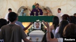 Relatives pray beside a coffin containing 16-year-old Jose Antonio Elena Rodriguez during his funeral in Nogales, Mexico, Oct.14, 2012.