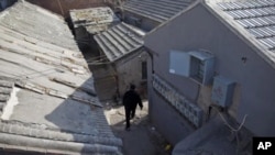 A man walks through the narrow alleys of a hutong in Beijing. 