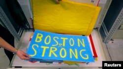 Archivist Marta Crilly holds a poster, an artifact saved from the makeshift Boston Marathon bombing memorial, at the City Archives in Boston, Massachusetts, March 27, 2014. 