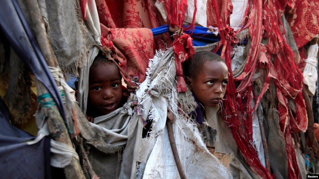 Pengungsi anak memperlihatkan wajah mereka diantara robekan kain yang menjadi tenda mereka di kompleks penampungan Sayyidka Howlwadag, Mogadishu, 19/8/2013. 
