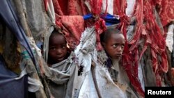 Pengungsi anak memperlihatkan wajah mereka diantara robekan kain yang menjadi tenda mereka di kompleks penampungan Sayyidka Howlwadag, Mogadishu, 19/8/2013. 