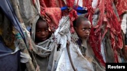 Displaced children peer through holes in the fabric used to make their temporary tent at Sayyidka camp in the Howlwadag district, south of Mogadishu, August 19, 2013. 