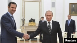 ປະທານາທິບໍດີ ຣັດເຊຍ ທ່ານ Vladimir Putin (ຂວາ) ຈັບມືກັບ ປະທານາທິບໍດີ ທ່ານ Bashar al-Assad ໃນລະຫວ່າງ ການພົບປະກັນ ຢູ່ທີ່ວັງ Kremlin ໃນນະຄອນຫຼວງ Moscow, Russia, ວັນທີ 20 ຕຸລາ 2015.