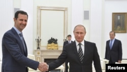 Russian President Vladimir Putin (R) shakes hands with Syrian President Bashar al-Assad during a meeting at the Kremlin in Moscow, Russia, October 20, 2015.