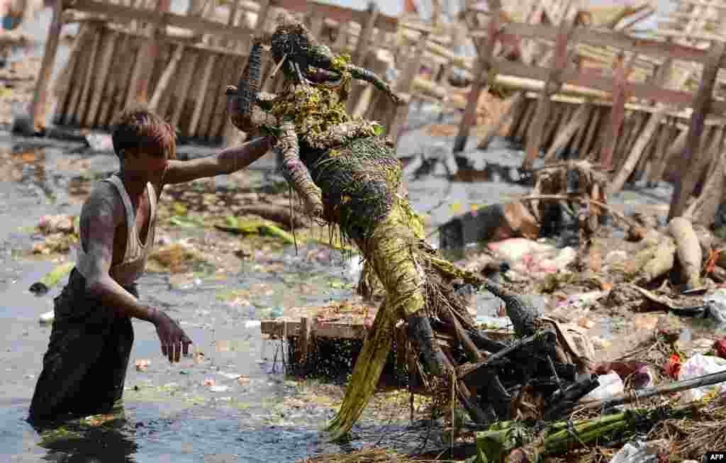 Workers remove religious offerings and frames of the idol of goddess Durga, which were immersed in the Yamuna river after the Durga Puja festival in New Delhi, India.
