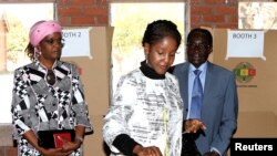 Zimbabwe's President Robert Mugabe (R) and his wife Grace (L) look on as their daughter Bona casts her vote in Highfields outside Harare July 31, 2013. Zimbabweans voted in large numbers on Wednesday in a fiercely contested election pitting veteran Presid