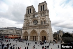 FILE - People walk past the entrance to the Notre-Dame cathedral in Paris, Feb. 8, 2013.