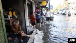 Một người đàn ông đang tát nước tràn vào nhà trong khi mực nước sông Chao Phraya dâng cao tràn lên đường phố trong quận Phranakhon của Bangkok hôm 24/10/11