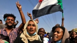 Sudanese protesters flash victory signs and lift natioanl flags as they demonstrate in Khartoum to denounce overnight detentions by the army of government members, on Oct. 25, 2021.