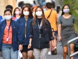 Office employees wearing facemasks walk along a street in Manila on January 30, 2020. -