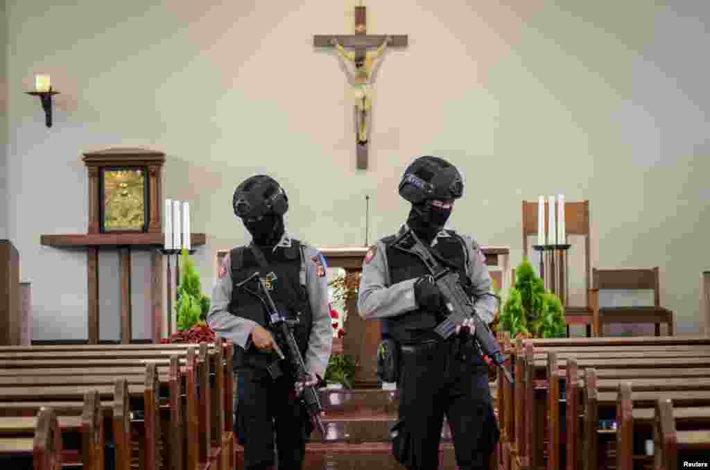 Dua orang polisi memeriksa Gereja Ignatius menjelang perayaan Malam Natal di Cimahi, Jawa Barat, dalam foto yang diambil oleh Antara.