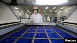 中国浙江省嘉兴的太阳能板工厂工人在把新制成的太阳能板作干燥处理。
