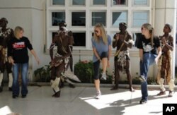 Study abroad students (from left) Gina Nuccio, Hillary Kinsey and Alyssa Crosby dance with Zulu musicians and performers wearing traditional tribal clothing.