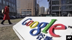 A woman walks past the logo of Google in front of its headquarters in Beijing January 12, 2011
